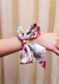 Silk scarflette with pink, green, and purple floral Mahjong tile print tied around wrist.