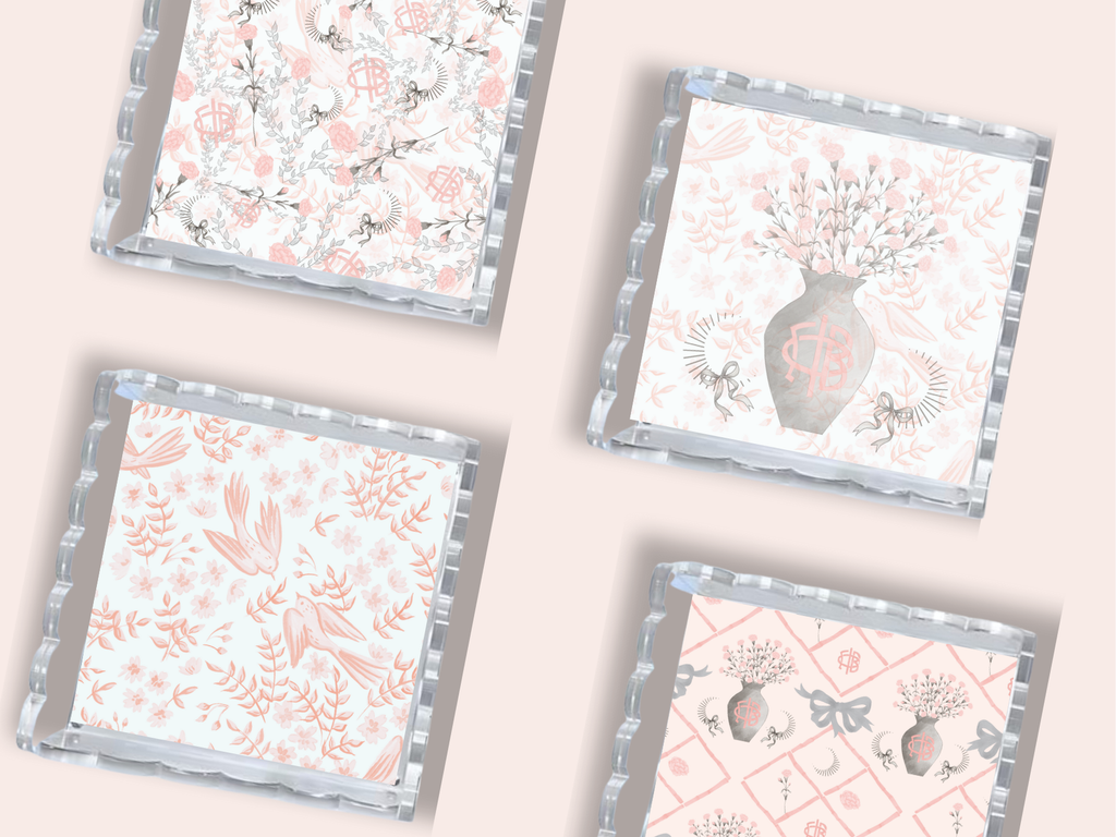 Three square trays with scalloped silver edges featuring pink floral, monogrammed vase, and deer patterns on white.