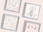Three square trays with scalloped silver edges featuring pink floral, monogrammed vase, and deer patterns on white.