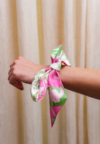 Pink and green floral silk scarf tied around wrist as a bracelet accessory.