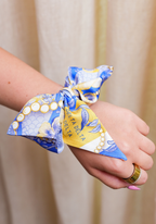 Blue and yellow patterned silk scarflette tied around wrist with Delta Delta Delta lettering.