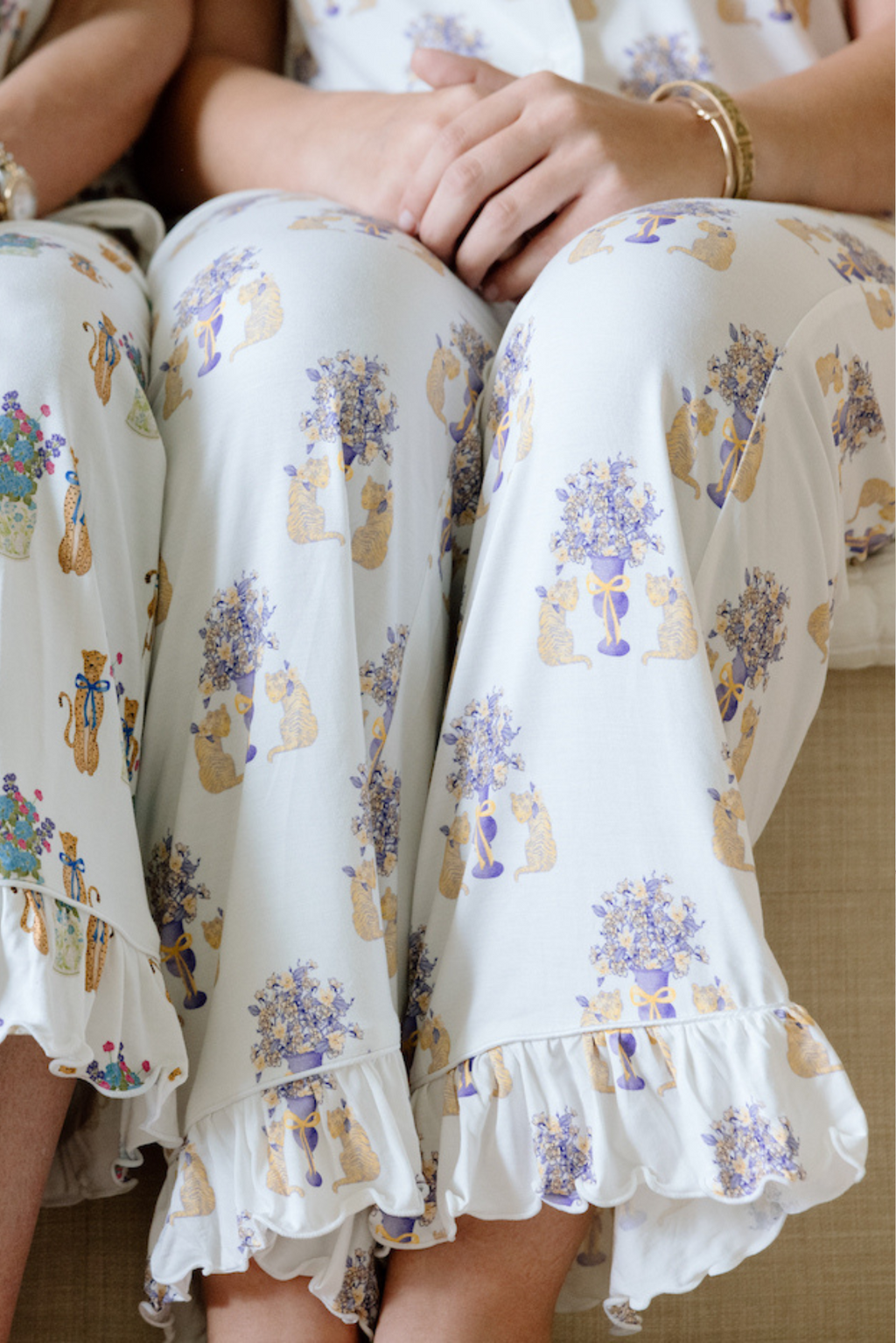 White pajama pants with ruffled hems and LSU Tigers floral and paw print pattern in purple and gold.