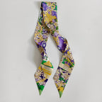 Purple Mardi Gras-themed scarflette with gold masks, beads, fleur-de-lis, and green accents.