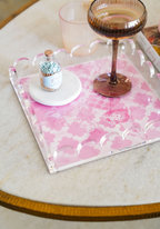 Pink scalloped tray with white floral pattern and raised sides on marble table.