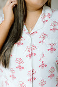 White pajama top with pink floral and Alpha Omicron Pi symbols, button-down style with collar and chest pocket.