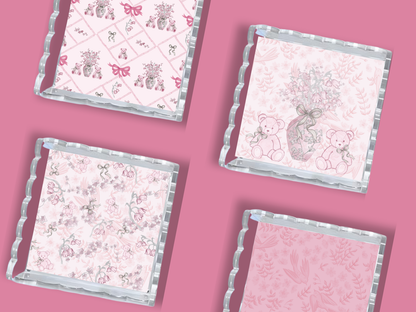 Set of four square acrylic trays with scalloped edges, each featuring pink and white patterns including alphabets, teddy.