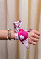 Pink and white floral scarflette tied around wrist with beaded bracelets.