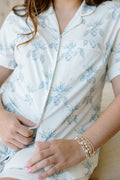 White pajama shorts set with light blue floral print, short sleeves, and button-up front.