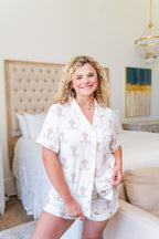 Woman wearing white short-sleeve pajama shorts set with light pink floral print.
