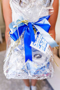 Clear cellophane-wrapped bid day basket with blue and white ribbons and a Happy Bid Day gift tag.