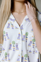 White pajama top with colorful Mardi Gras mask and bead prints, button-up style.