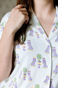 White pajama top with colorful Mardi Gras-themed print featuring masks and beads, buttoned front.