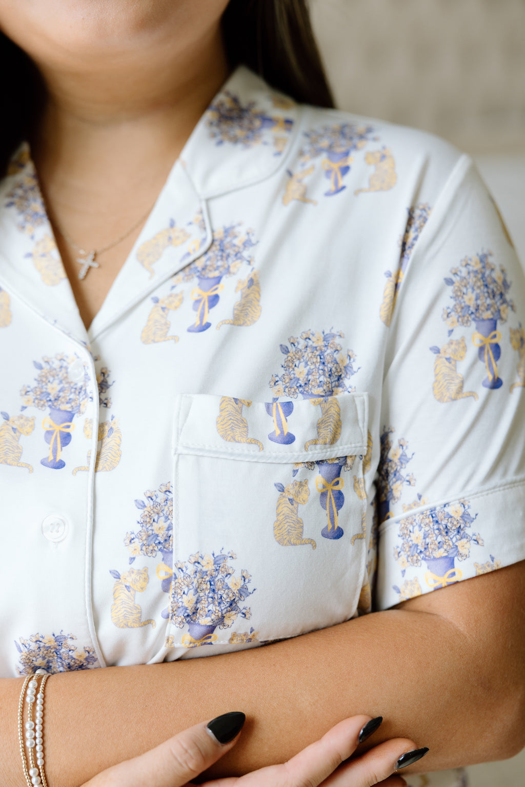 White short-sleeve pajama top with purple and gold LSU tiger floral print and chest pocket.