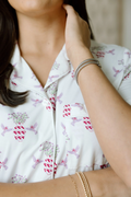 White pajama top with pink and red floral and geometric print, black piping along collar and button line.