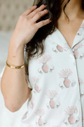 White pajama top with pink floral and Gamma Phi Beta crest print, notched collar, and button front detail.