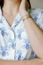 White pajama top with blue floral and anchor print, featuring a chest pocket and button-down front.