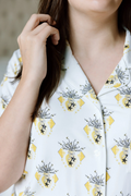 White pajama shirt with yellow diamond and black emblem pattern, notched collar, and buttons.